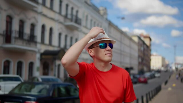 Guy tourist in a hat walks along a city street, inspects the surroundings, camera movement
