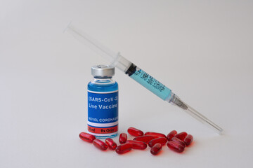 Vaccine, syringe, and red capsules on a white background. Vaccine for the SARS-CoV-2 concept.