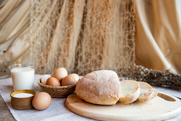 Bread eggs salt and milk on wooden plates on a background in warm colors