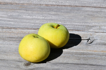Closeup on fresh and recently picked yellow apples placed on wooden board