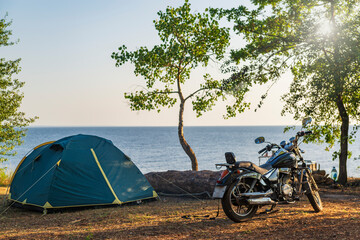 Motor bike and tent at the sea coast.