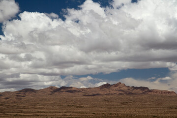Fototapeta na wymiar Arid landscape. View of the desert and rocky mountains under a dramatic sky with beautiful clouds. 