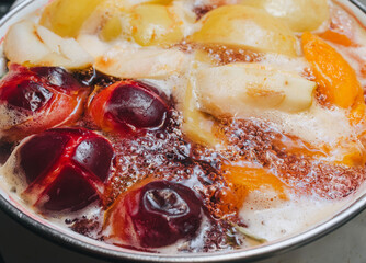 Fruit compote: apricots, plums, apples, cherries are cooked in a metal pan in boiled water with bubbles. Making juice.