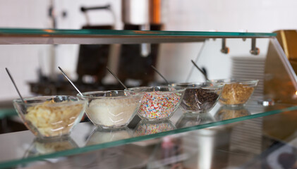 Closeup shot of sweet sprinkle toppings in bowls in a glass stand