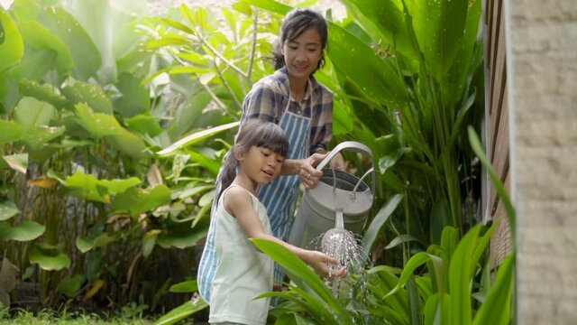 happy mother and daugther watering her garden together at home