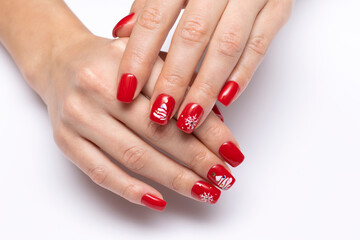 New Year's red manicure with painted white snowflakes and a Christmas tree on short square nails on a white background close-up