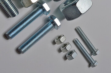 bolts and nuts of different sizes are laid out on a light background.