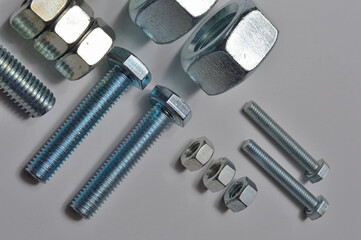 bolts and nuts of different sizes are laid out on a light background.