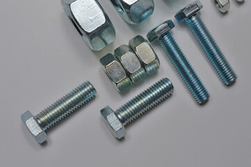 bolts and nuts of different sizes are laid out on a light background.