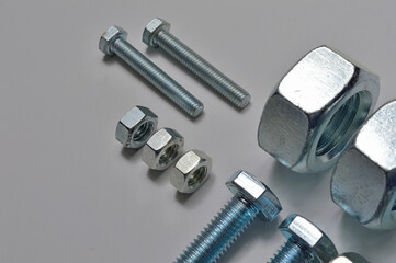 bolts and nuts of different sizes are laid out on a light background.