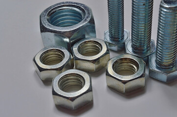 bolts and nuts of different sizes are laid out on a light background.