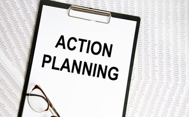 A sheet of paper with the inscription ACTION PLANNING is fixed on the tablet, against the background of accounting.