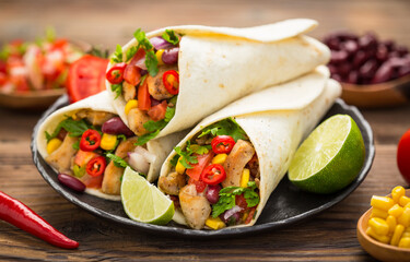 Fresh tortilla wraps with chicken meat and vegetables on the wooden table