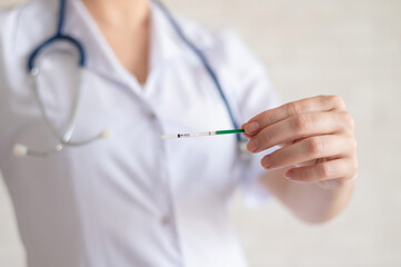 A faceless female doctor holds a negative quick pregnancy test. Gynecologist in a medical coat and...