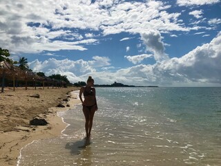 Pretty blonde female model on the sandy beach of Playa Ancon in Cuba in a panorama of a tropical paradise enjoying her relaxing vacation