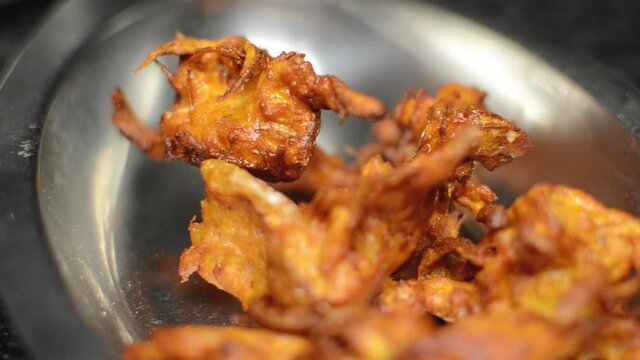 Close up shot of Indian pakoras or onion bhajis stacked in a stainless steel plate