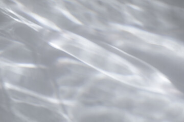 Fototapeta premium Blurred water texture overlay effect for photo and mockups. Organic drop diagonal shadow and light caustic effect on a white wall. Shadows for natural light effects