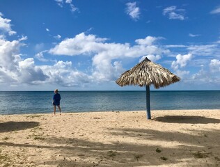 Pretty blonde female model on the sandy beach of Playa Ancon in Cuba in a panorama of a tropical paradise enjoying her relaxing vacation