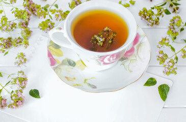 herbal medicinal tea with oregano flowers in a cup close-up. background with a cup of tea with oregano flowers macro.