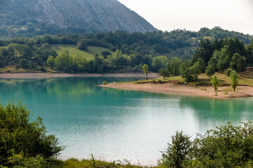 Lake Castel San Vincenzo, dam, with a lot of vegetation and rocky mountain in the background,...