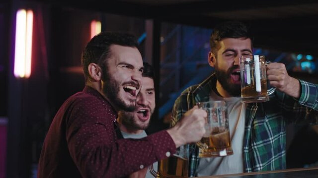 Great looking guys very emotional watching a match on tv in a sport bar they celebrating the victory cheers with glasses of beer they are very excited. Shot on ARRI Cinema Camera