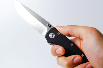 A folding knife with a black handle on a white background, open and closed. Paracord lanyard on the knife. Tactical folding knife in close-up. Knife in a man's hand