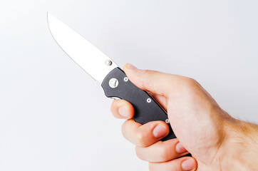 A folding knife with a black handle on a white background, open and closed. Paracord lanyard on the knife. Tactical folding knife in close-up. Knife in a man's hand
