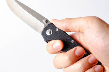 A folding knife with a black handle on a white background, open and closed. Paracord lanyard on the knife. Tactical folding knife in close-up. Knife in a man's hand