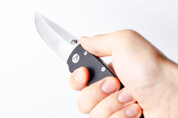 A folding knife with a black handle on a white background, open and closed. Paracord lanyard on the knife. Tactical folding knife in close-up. Knife in a man's hand