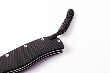 A folding knife with a black handle on a white background, open and closed. Paracord lanyard on the knife. Tactical folding knife in close-up