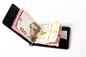 Banknotes Ukrainian hryvnia and dollars on a white background in close-up. Money in a black wallet, money clip Dollars and hryvnia