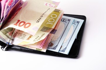 Banknotes Ukrainian hryvnia and dollars on a white background in close-up. Money in a black wallet, money clip Dollars and hryvnia