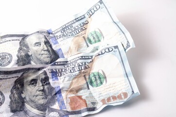 Crumpled, burnt dollar bills on a white background in close-up and in a man's hand
