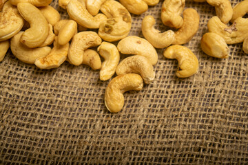 A pile of cashew nuts on burlap with a rough texture surface texture. Close up.