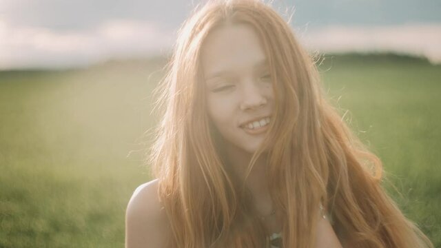 Portrait of young redhead girl enjoying nature and sunlight in field. redheaded young woman with freckles. Happy young girl in sunset lights. Freedom concept.
