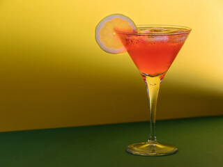 Red cocktail in a glass with a lemon slice