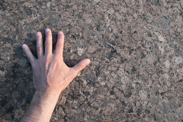 The hand touches the granite rock. Point of view. Copy space.