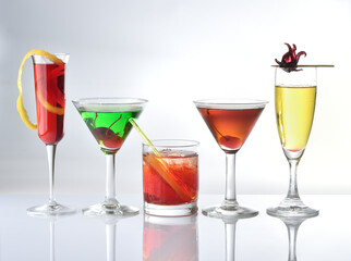 five different glasses of colorful cocktails on a white background