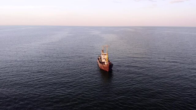 Drone flies over a fishing ship at sunset. Fishing boat trawler ship sailing on a sea surface. Top view. Aerial view fishing ship offshore moving to harvest seafood on the beach, ocean surface