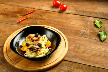 Black plate with spaghetti nests stuffed with assrty chicken fillet and mushrooms on a stand. Copy space