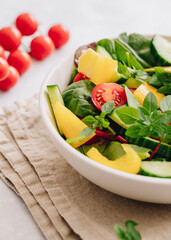 Vegetable salad close up with olive oil in white bowl on linen napkin