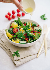 Vegetable salad with olive oil in white bowl on linen napkin