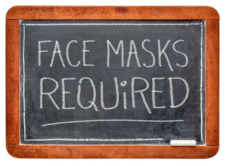 Obraz premium face masks required - white chalk handwriting on a slate blackboard, business sign during the coronavirus covid-19 pandemic and social distancing