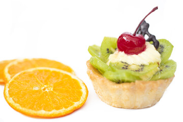 Cake with kiwi cherries and custard, near slices orange. White background,