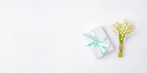 Flat lay festive composition with white flowers and a gift box on a white background