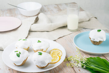 Cupcake with white cream in a plate. Nearby lies a bouquet of lilies of the valley