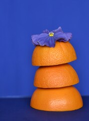 Tower of orange oranges and blue flowers on a blue, bright and helthy life