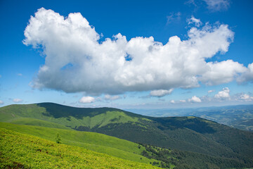 Obraz premium Dramatic white clouds on blue sky over green Carpathian mountains. Tops of the Carpathian mountains. Beautiful landscape with greenery and clouds. Beauty nature landscape. Mountains against the sunny 