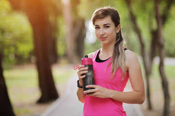 Beautiful fitness athlete runner woman drinking water in the park. Water bottle