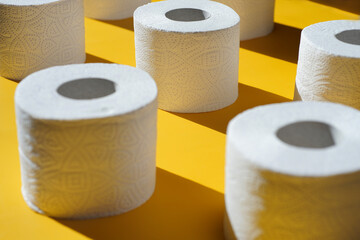 Rolls of new toilet paper lie on a yellow background